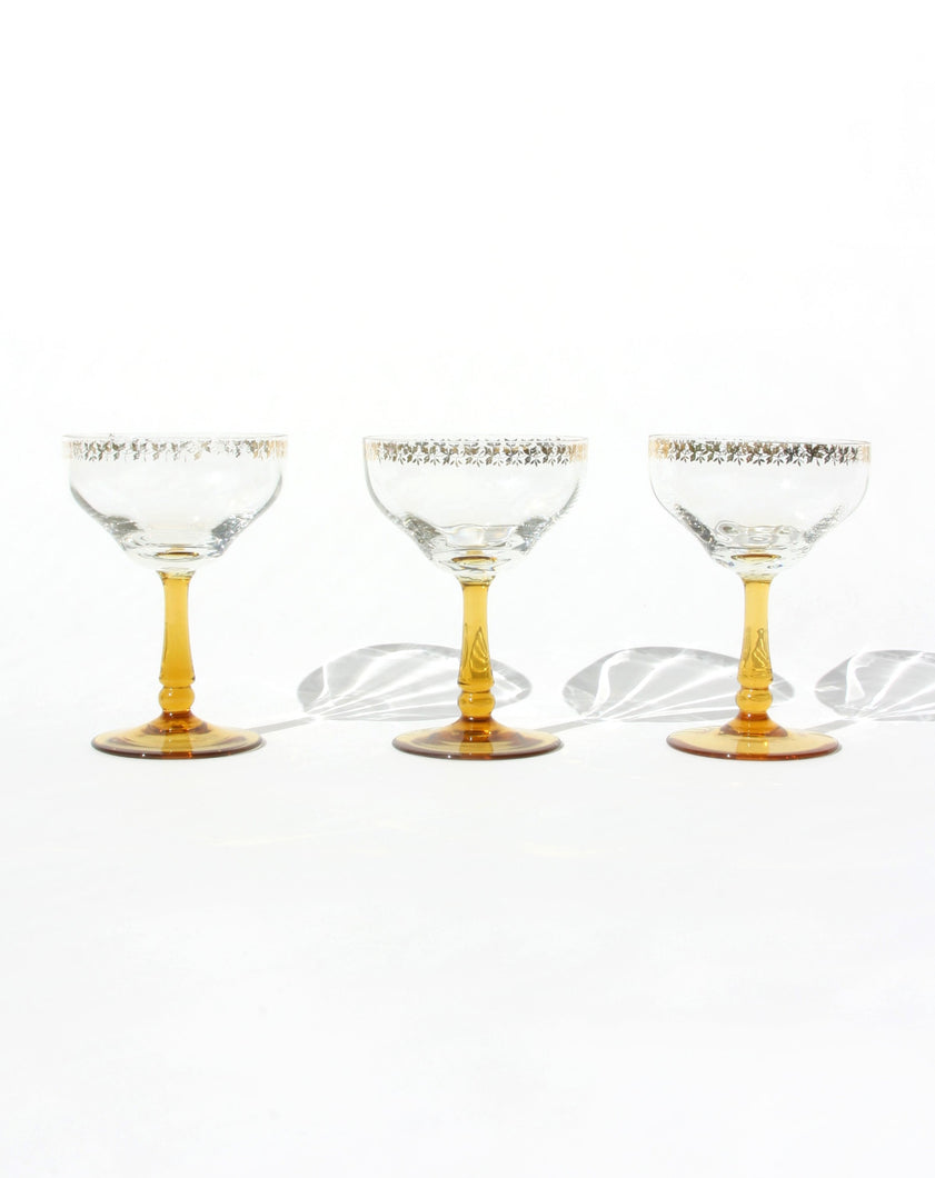 Set of three frosted glass champagne coupes with an amber handle. Shop the range of hand sourced glassware and ceramics by Rebecca Arts online.